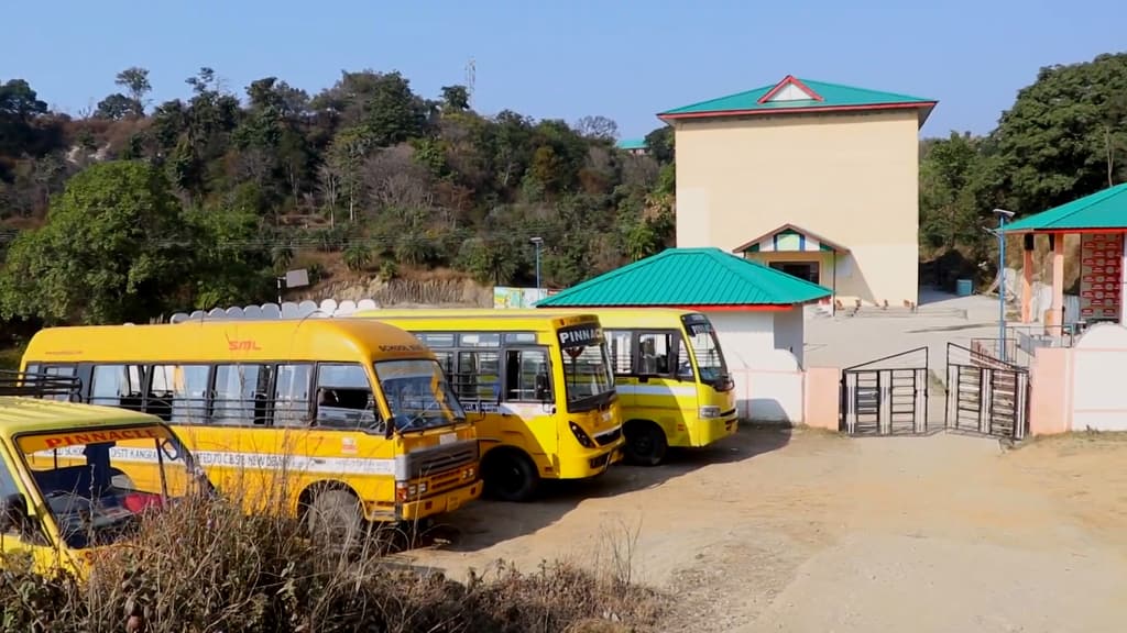 The school gate and building at Baroh, with the yellow school buses in the yard
