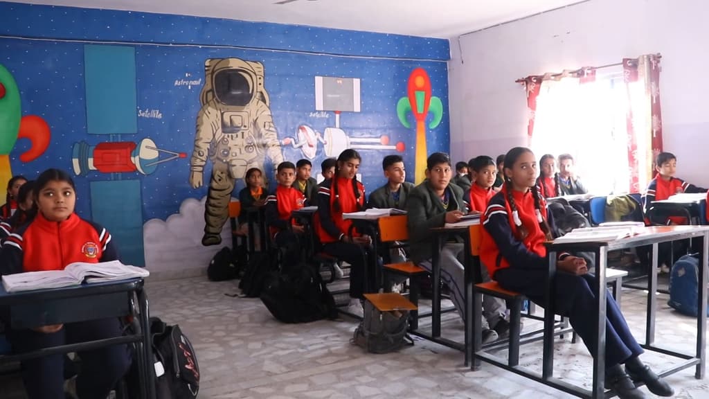 Primary students at their desks in a classroom with an astronaut and rocket mural