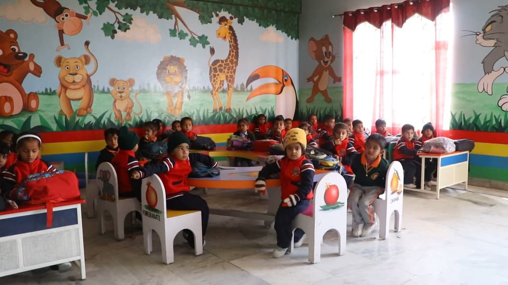 Kindergarten children at small tables beneath a painted animal mural